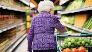 anziana signora al supermercato con carrello pieno di verdure