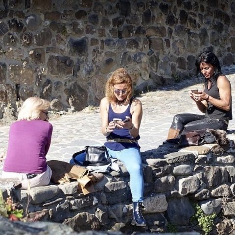 Giovani donne consultano il cellulare in riva al fiume