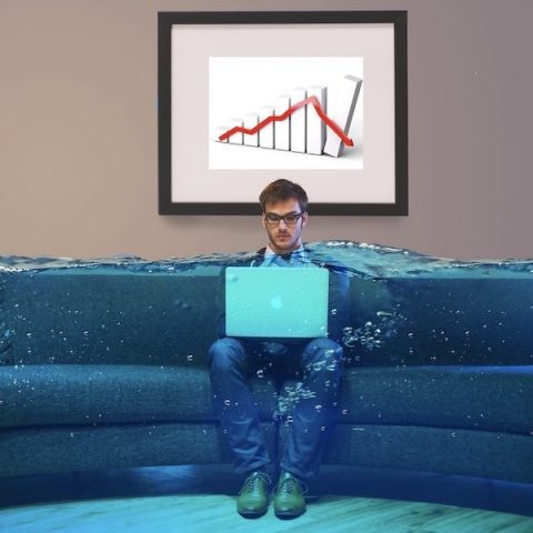 Un giovane uomo è seduto su un divano, concentrato davanti a un computer portatile. Sta valutando scelte strategiche relative a piani finanziari e assicurativi, riconoscendo la complessità di tali argomenti. La sua attenzione è rivolta al monitor del computer mentre esamina queste questioni.
